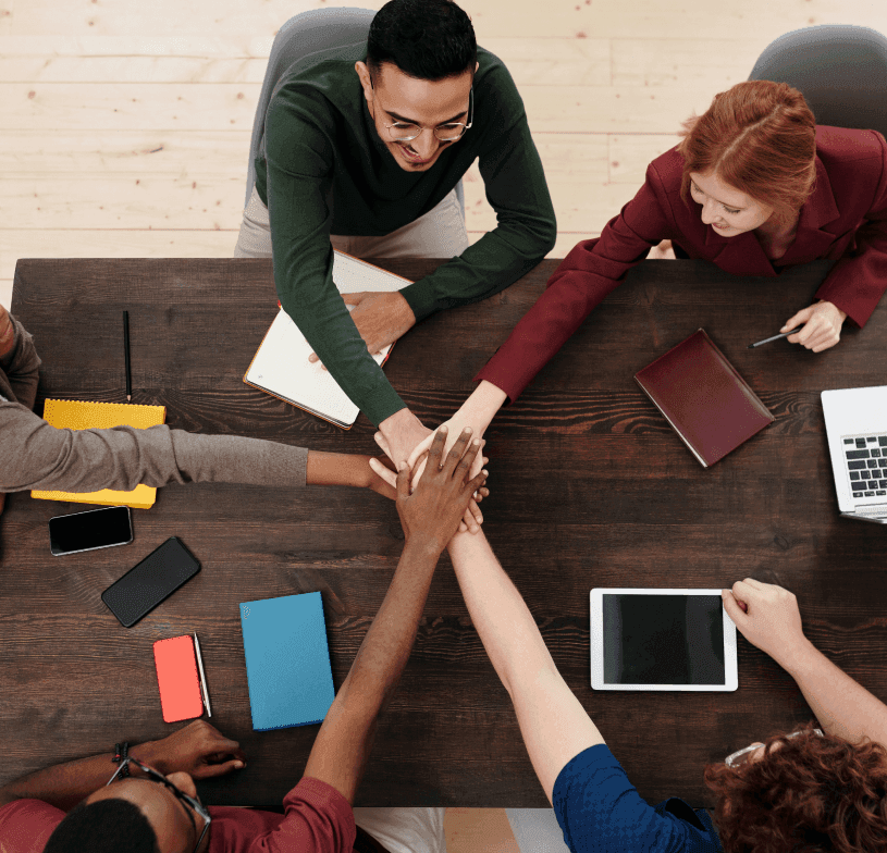 Equipo juntando las manos sobre una mesa de trabajo